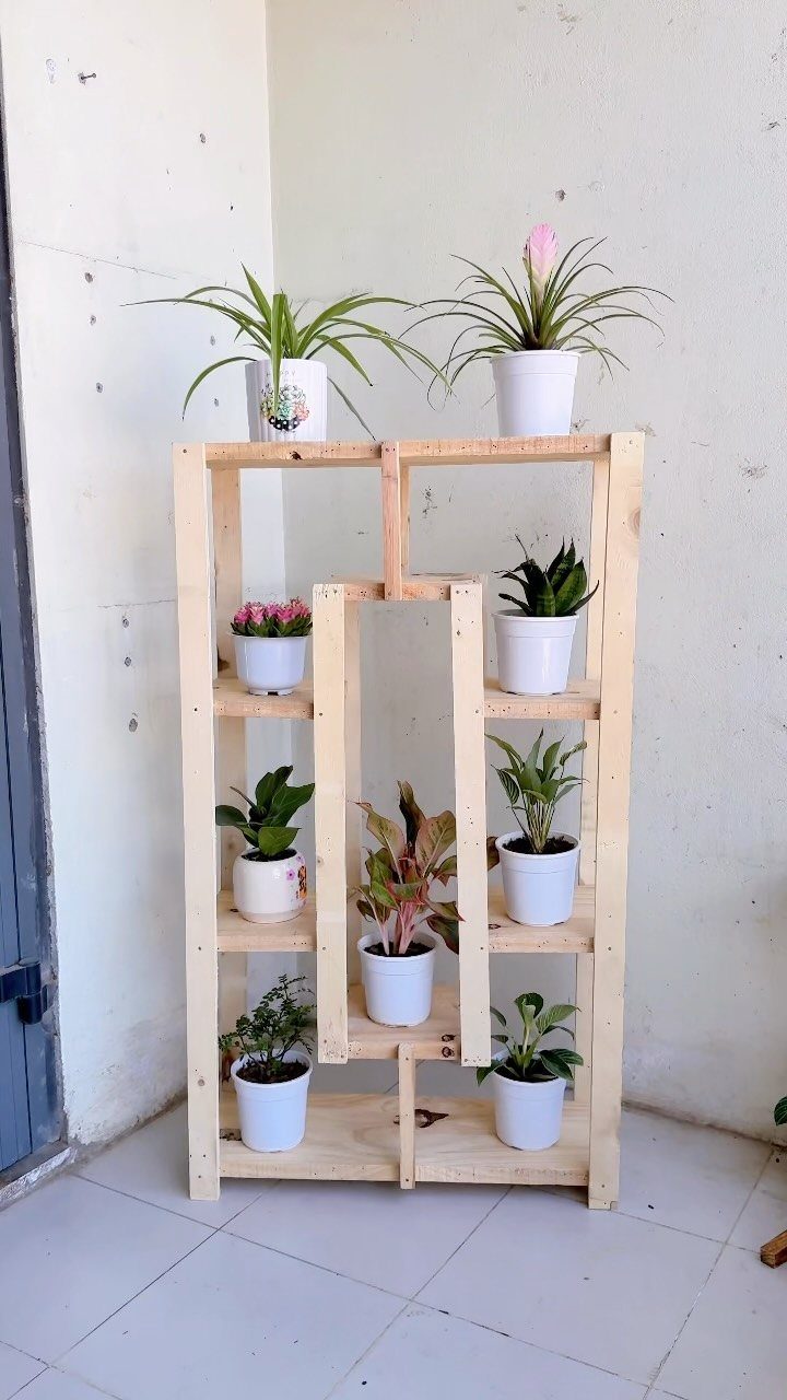 2x4 Plant Stand Ideas: 6 Builds for Indoors and Out 2 Wooden 2x4 plant stand with multiple shelves holding various potted green plants.