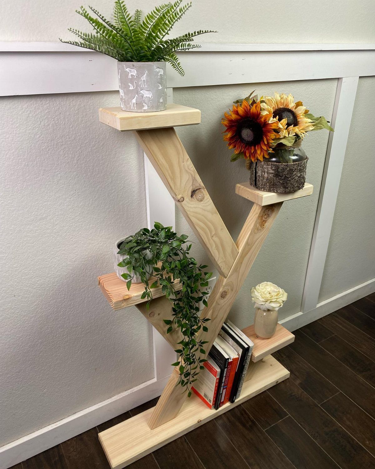 2x4 Plant Stand Ideas: 6 Builds for Indoors and Out 5 Wooden 2x4 plant stand with potted greenery and sunflowers against a white wall.