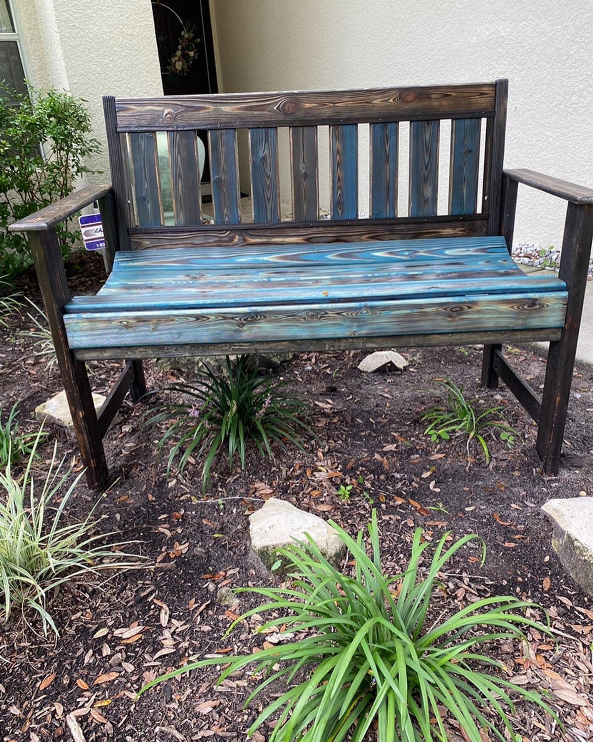What Can You Do With Burned and Stained Wood? 5 Ideas 3 Wooden garden bench with blue and brown stained wood and charred grain details.