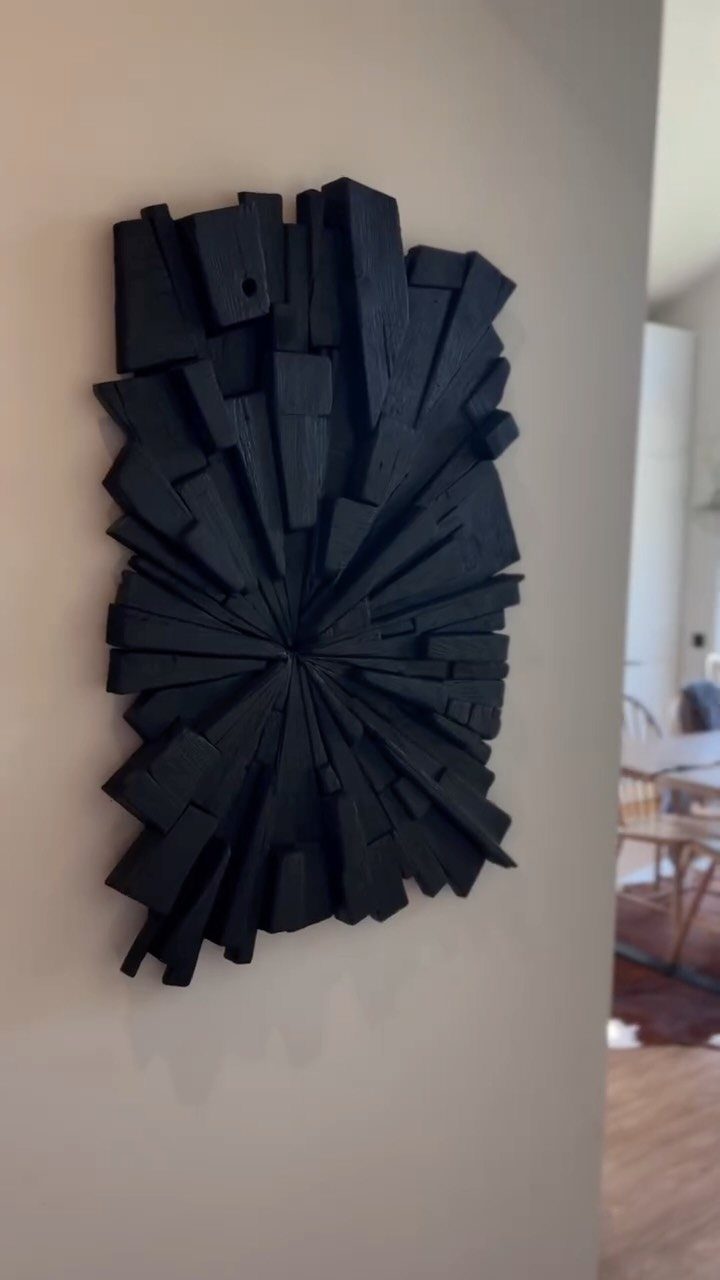 Burned Wood Finish Ideas: 8 Charred Projects for Home 4 Charred black wood sculpture with radial blocks mounted on a neutral wall.
