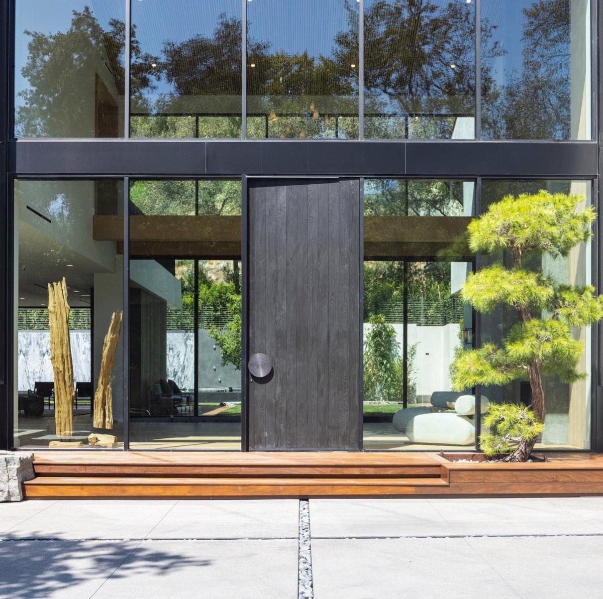 Burned Wood Finish Ideas: 8 Charred Projects for Home 7 Charred black wooden door at the entrance of a modern glass house.