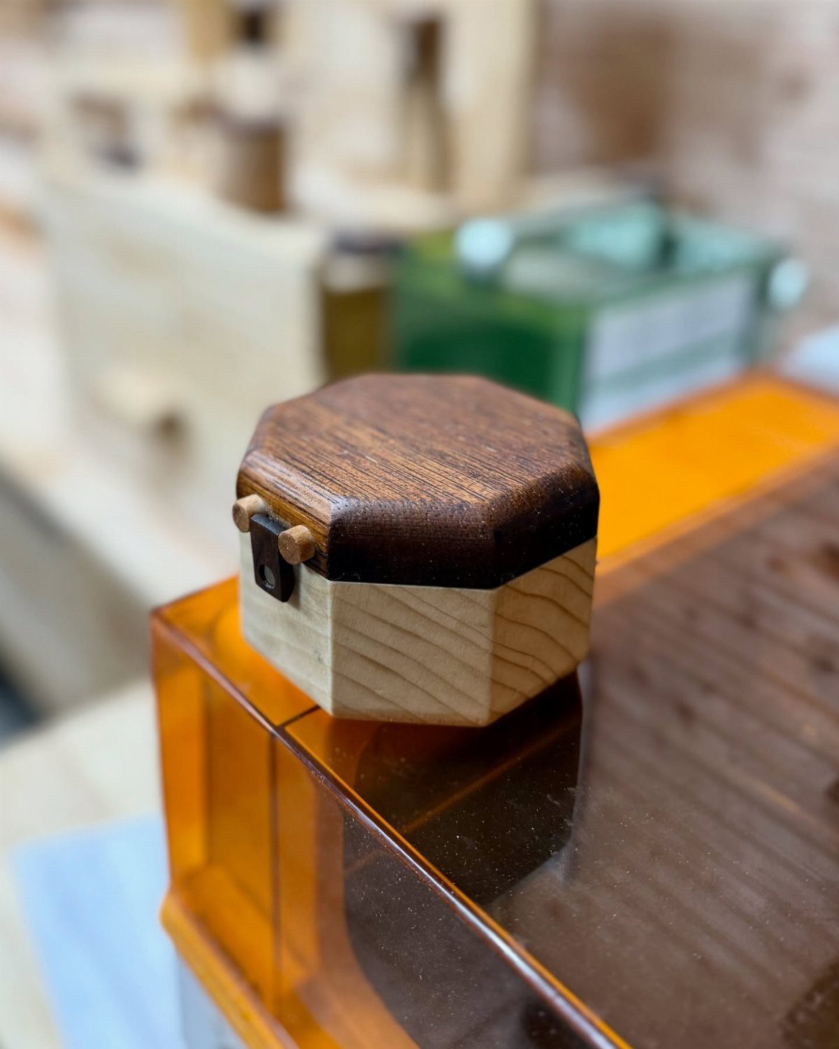 Burned Wood Finish Ideas: 8 Charred Projects for Home 5 Hexagonal wooden box with a charred dark brown lid on an orange surface.