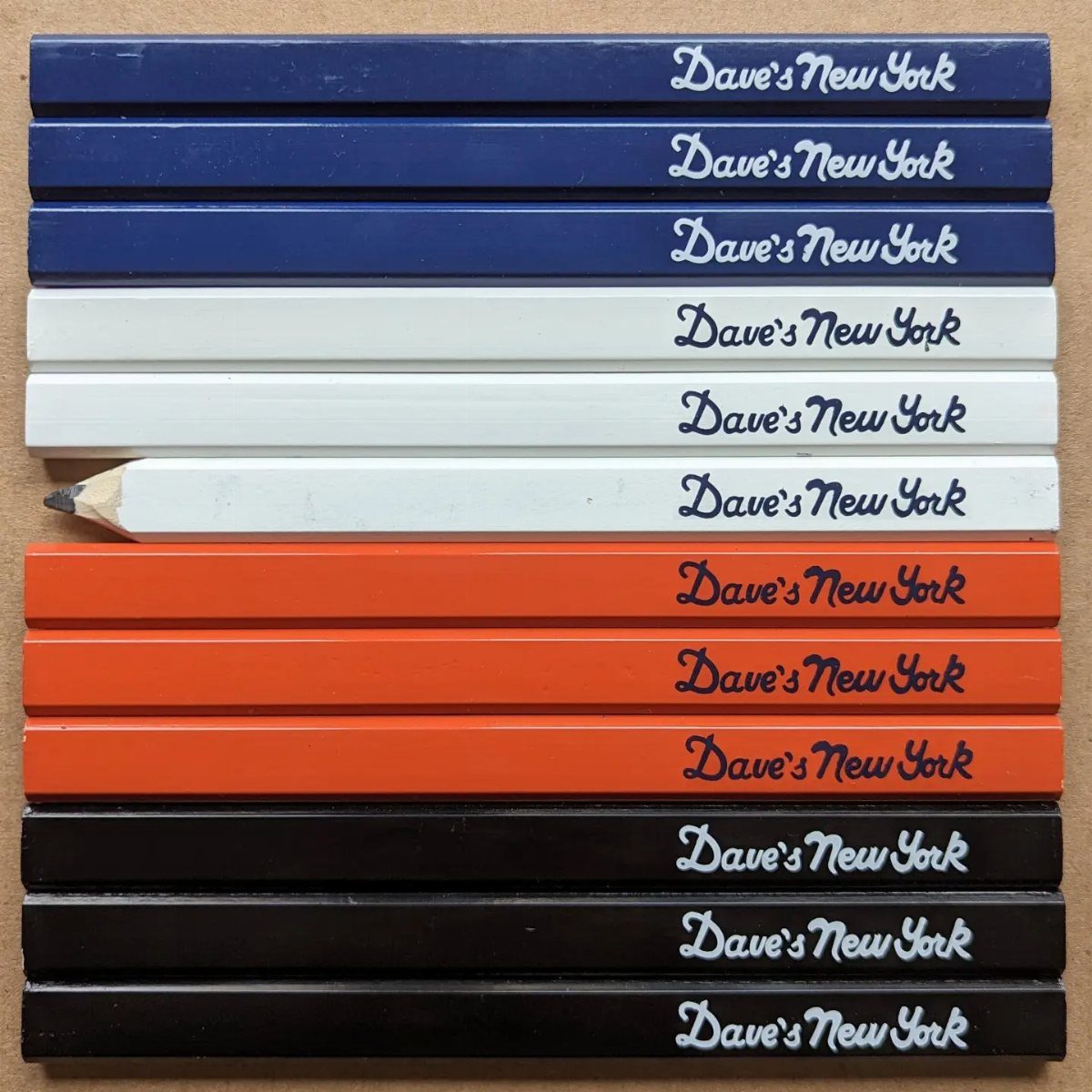 Carpenter Tools with Name: 7 Basics for Every Toolbox 2 Flat rectangular carpenter pencils in blue, white, orange, and black with printed text.