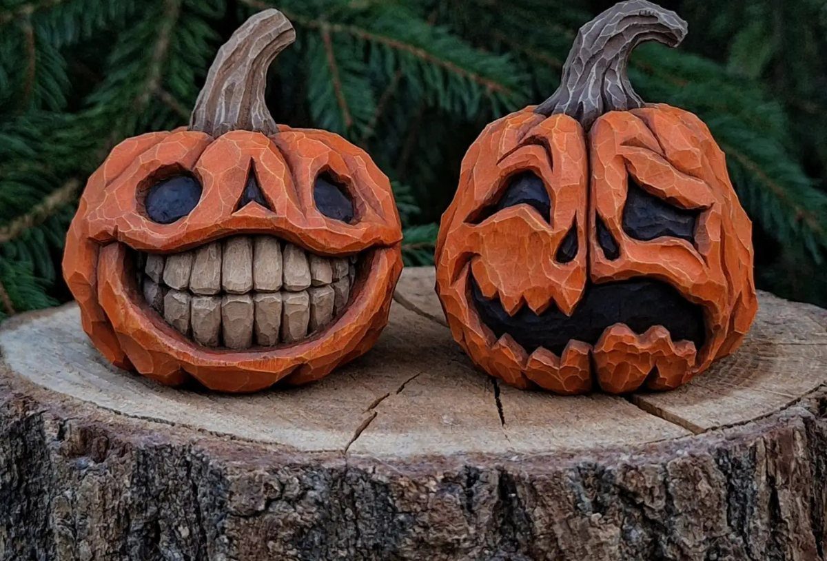 Two carved wooden pumpkins with expressive faces resting on a natural log slice.