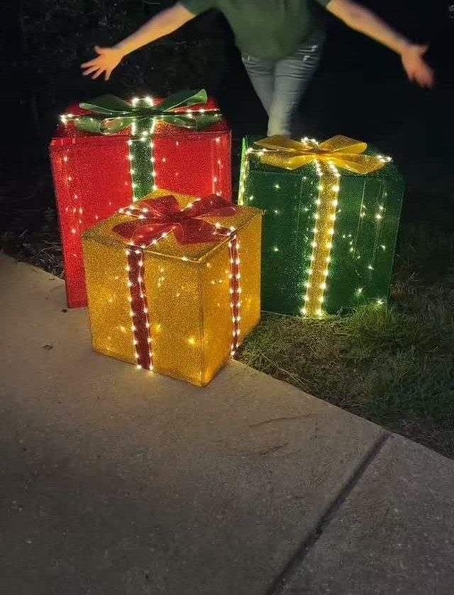 12 Christmas Decorations DIY for Outdoor Spaces 5 Glowing red, green, and yellow gift boxes with lights on a night lawn.