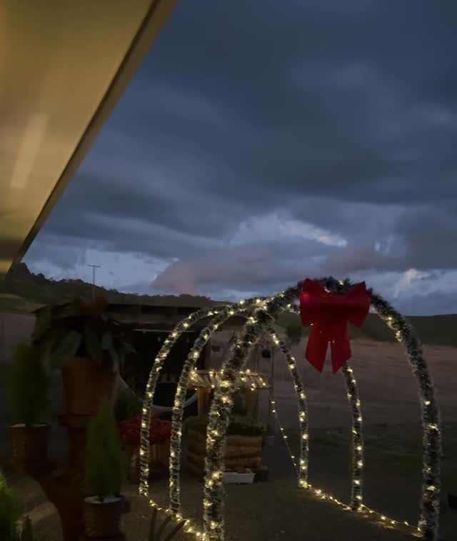 12 Christmas Decorations DIY for Outdoor Spaces 11 Illuminated light arches with a red bow as outdoor Christmas decorations at twilight.