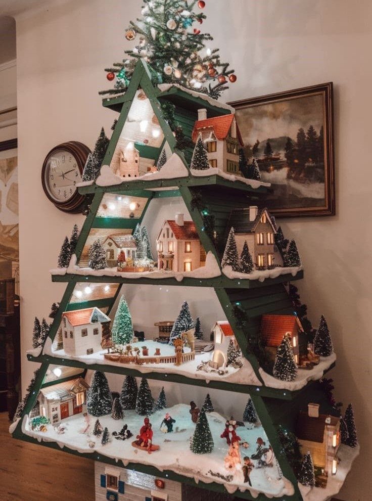 8 Christmas Pallet Projects for Holiday Decor 5 Green tree-shaped wooden shelf decorated with miniature winter village houses and fairy lights
