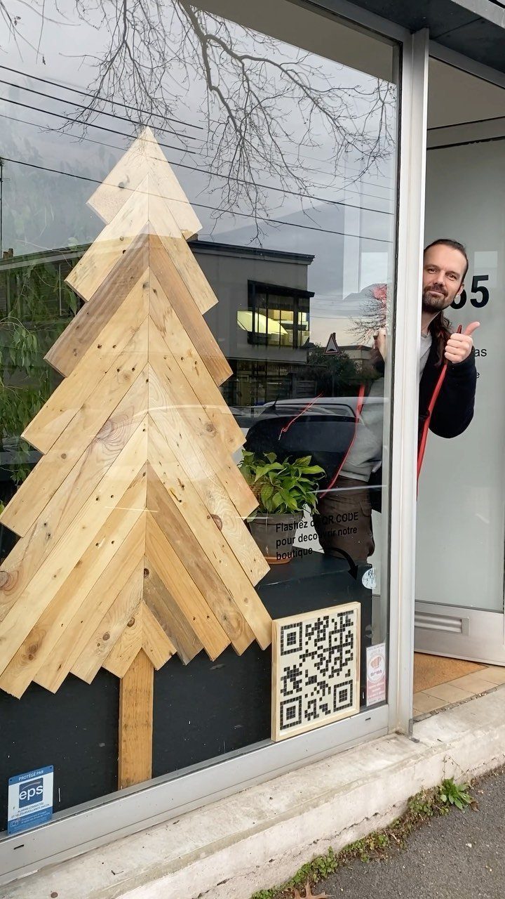 8 Christmas Pallet Projects for Holiday Decor 3 Wooden pallet Christmas tree display in a store window with a man posing nearby.