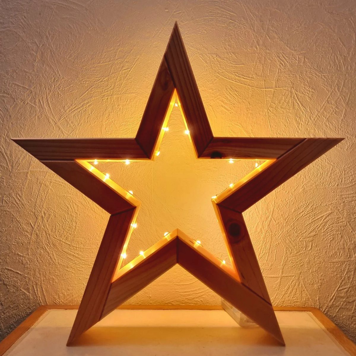 8 Christmas Pallet Projects for Holiday Decor 1 Large wooden star decoration with warm yellow fairy lights glowing inside.