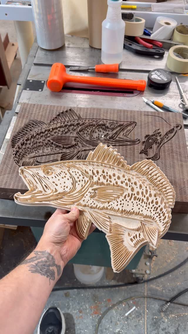 CNC Router Projects and Ideas: 10 Wood Pieces to Make 10 Wooden fish carving held by a hand over a workbench with tools.