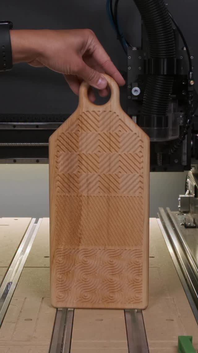 CNC Router Projects and Ideas: 10 Wood Pieces to Make 7 Wooden cutting board with carved geometric patterns held in front of a CNC router.