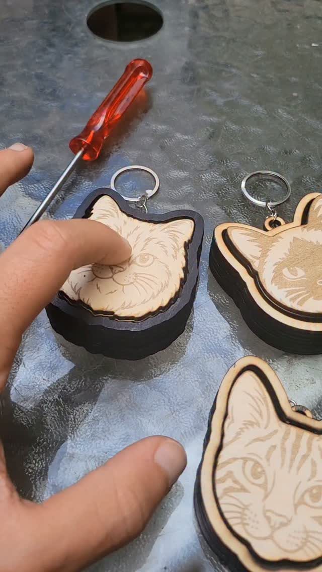 CNC Router Projects and Ideas: 10 Wood Pieces to Make 9 Cat-shaped wooden keychains with engraved details resting on a glass surface.