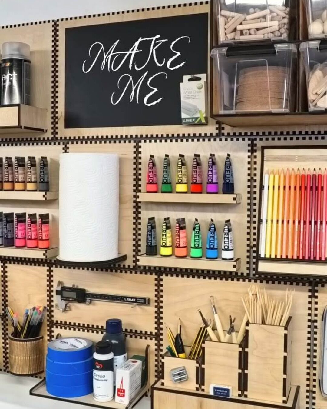 Chalkboard wall with 'MAKE ME' text surrounded by organized craft supplies and tools.