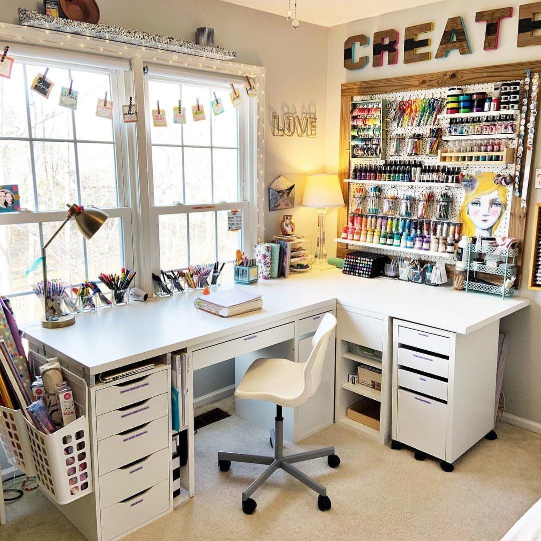 L-shaped white craft desk with a large pegboard wall filled with colorful supplies.