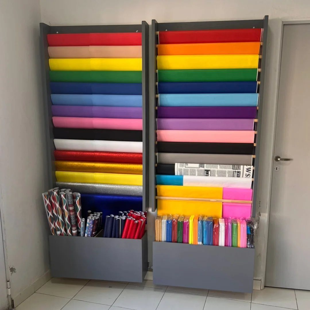 Colorful wrapping paper rolls organized horizontally in two tall grey storage units.