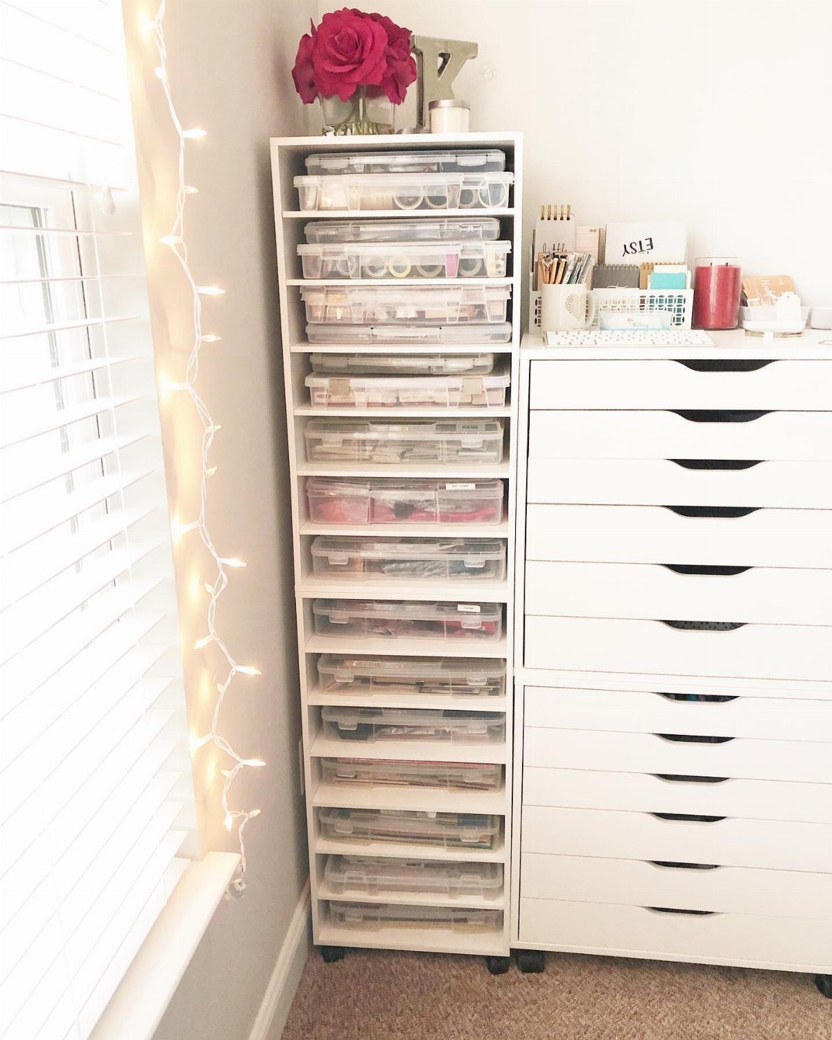 Tall white storage unit with clear plastic drawers filled with various craft supplies.
