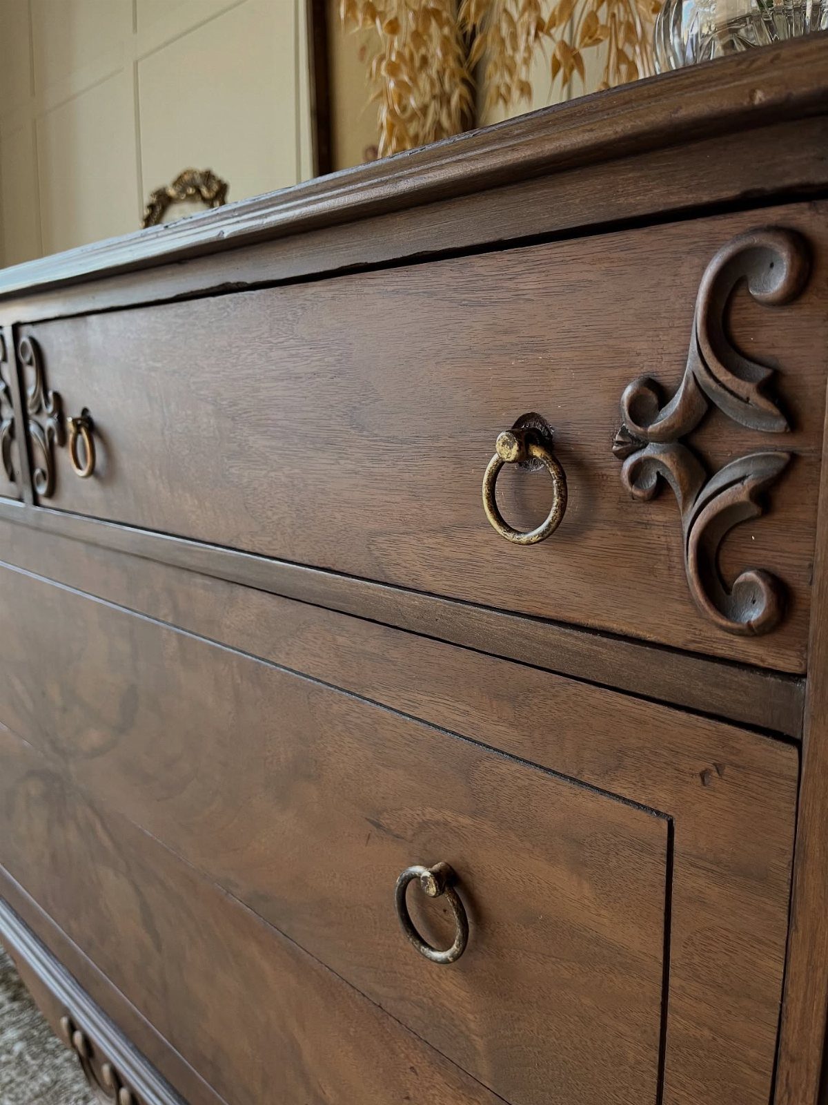 Dark brown wooden dresser with ornate carvings and brass ring drawer pulls