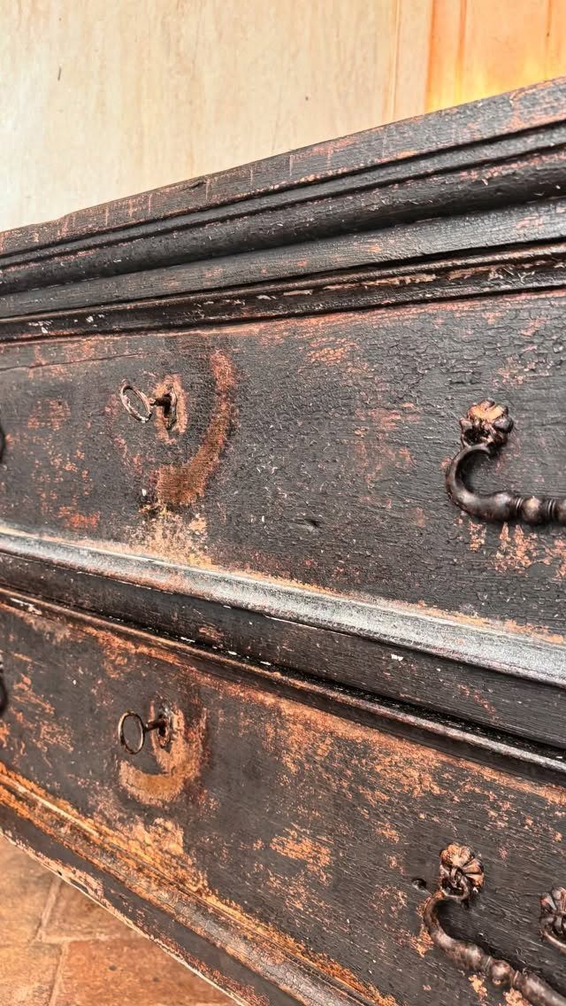 Distressed dark wood dresser with peeling paint and ornate metal hardware