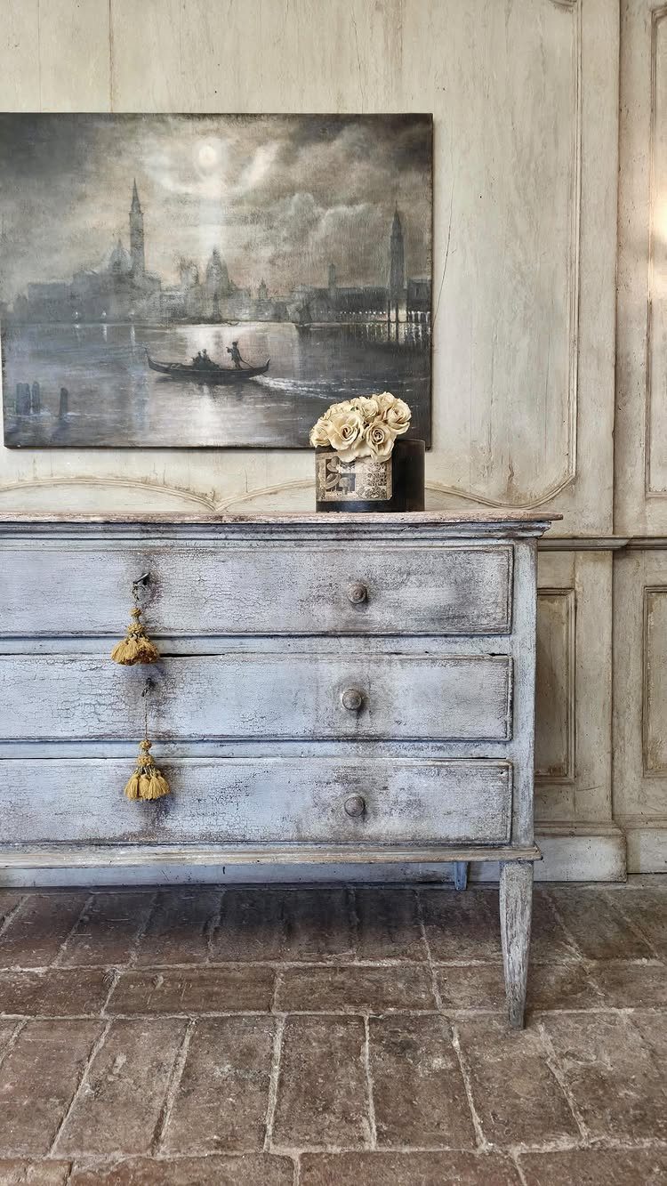Light blue distressed wooden dresser with worn edges and a painting above it.