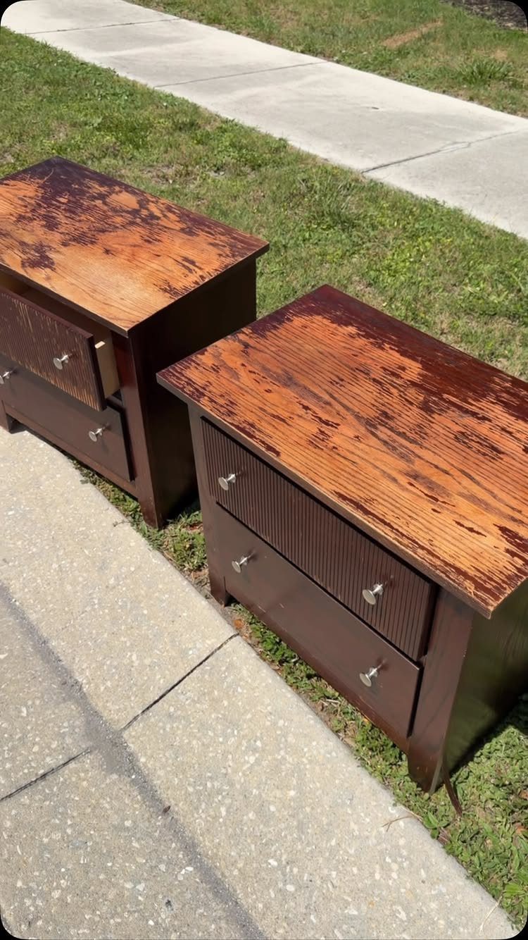 Two brown wooden nightstands with heavily distressed, worn-down tops on a concrete sidewalk.