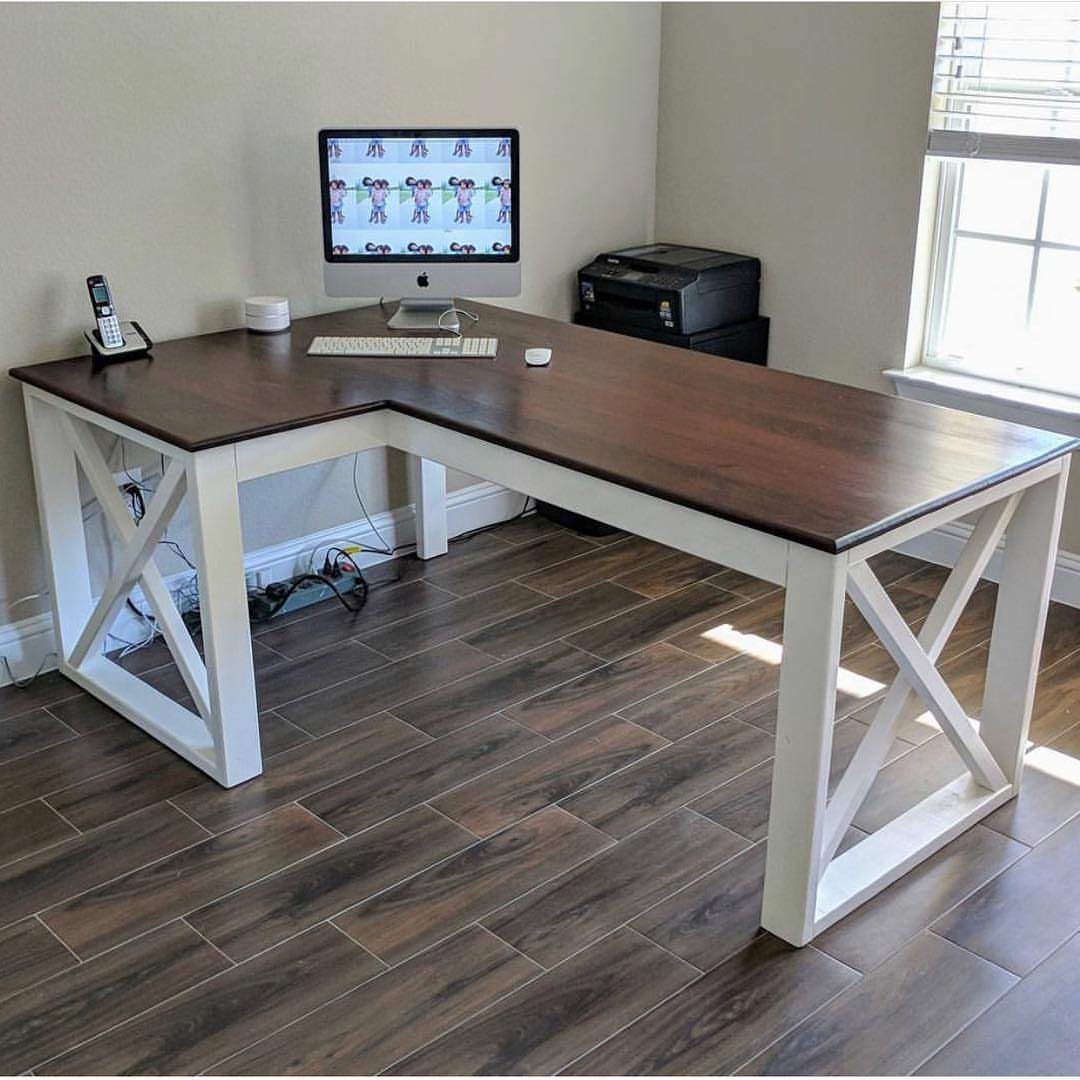 L-shaped wooden desk with dark brown top and white X-frame legs in a room