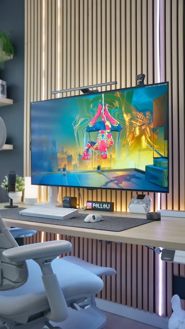 Modern gaming setup with ultrawide monitor on a light wood desk against slatted wall.