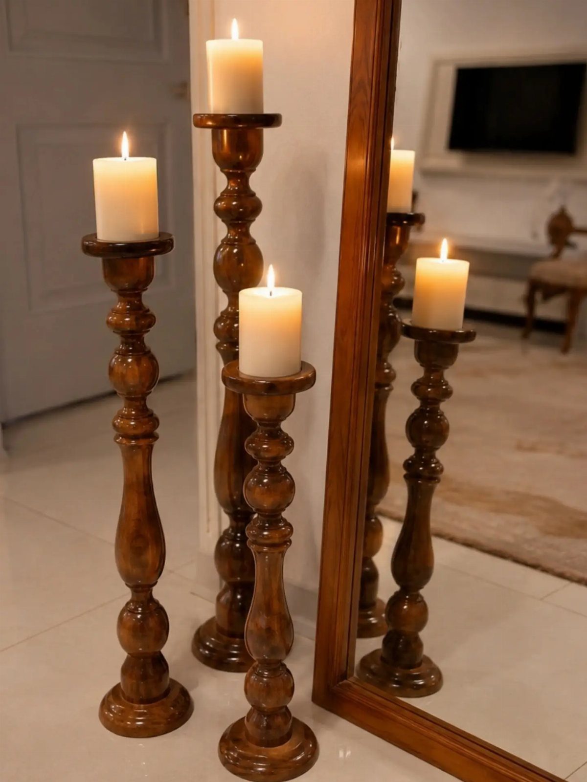 14 DIY Home Decor Wood Ideas for Every Room in the House 6 Three tall turned wooden candle holders with lit white pillar candles beside a mirror.