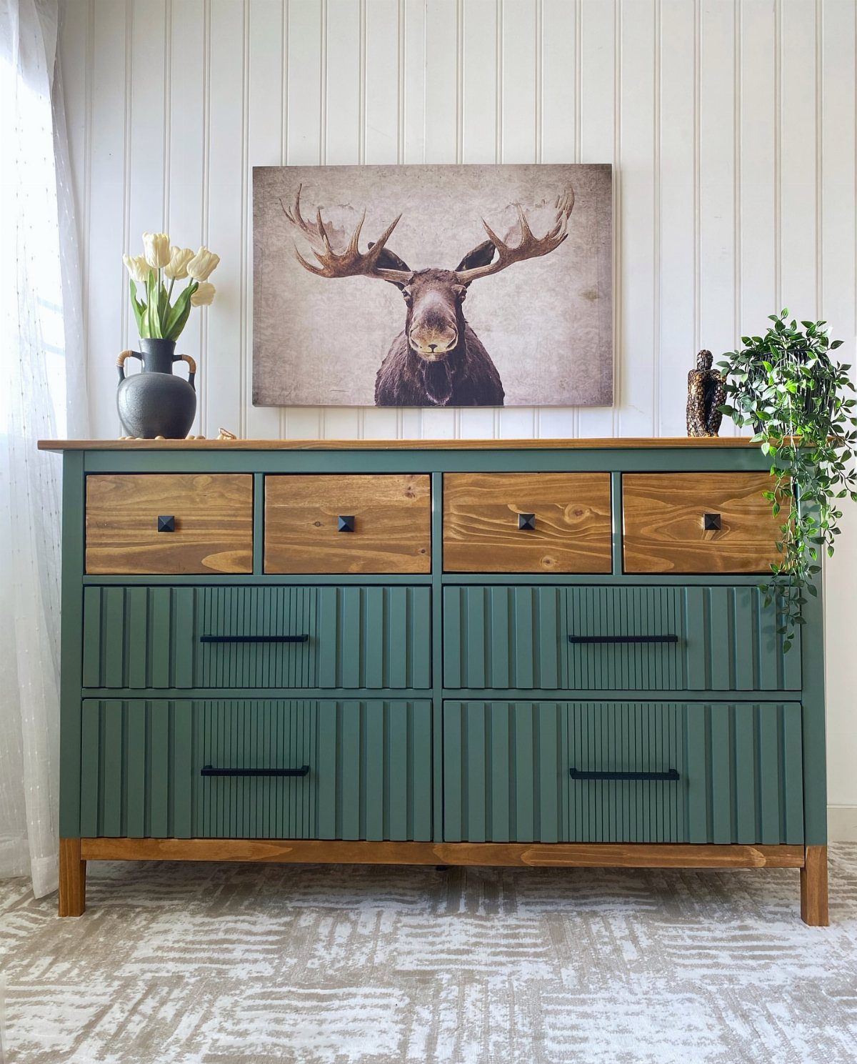 Green painted dresser with natural wood top drawers and a moose painting above.