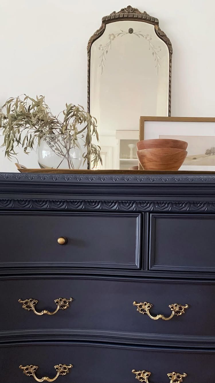 Dark navy blue painted dresser with ornate gold metal drawer pulls and mirror.