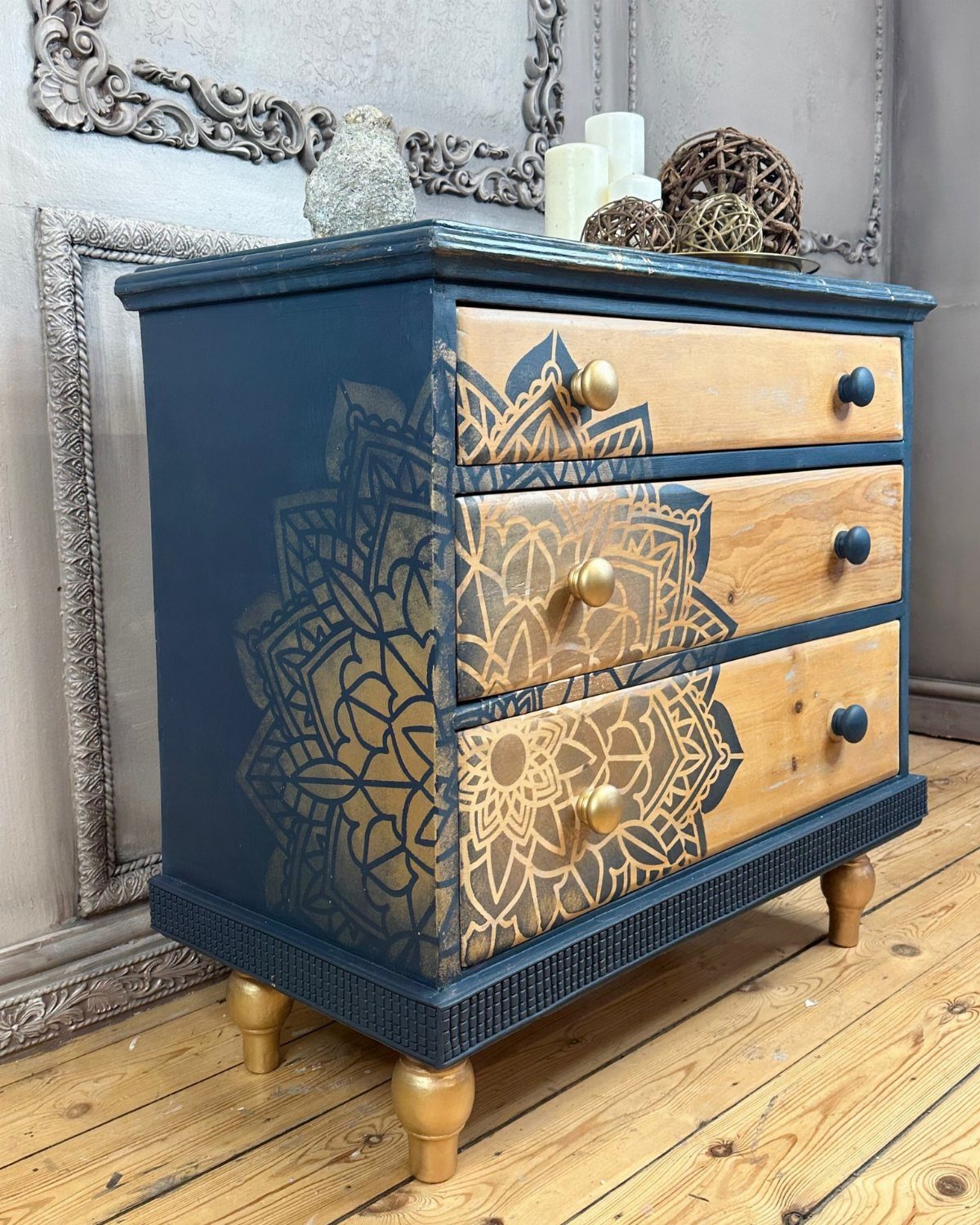 Dark blue dresser with natural wood drawers featuring a gold mandala stencil design.
