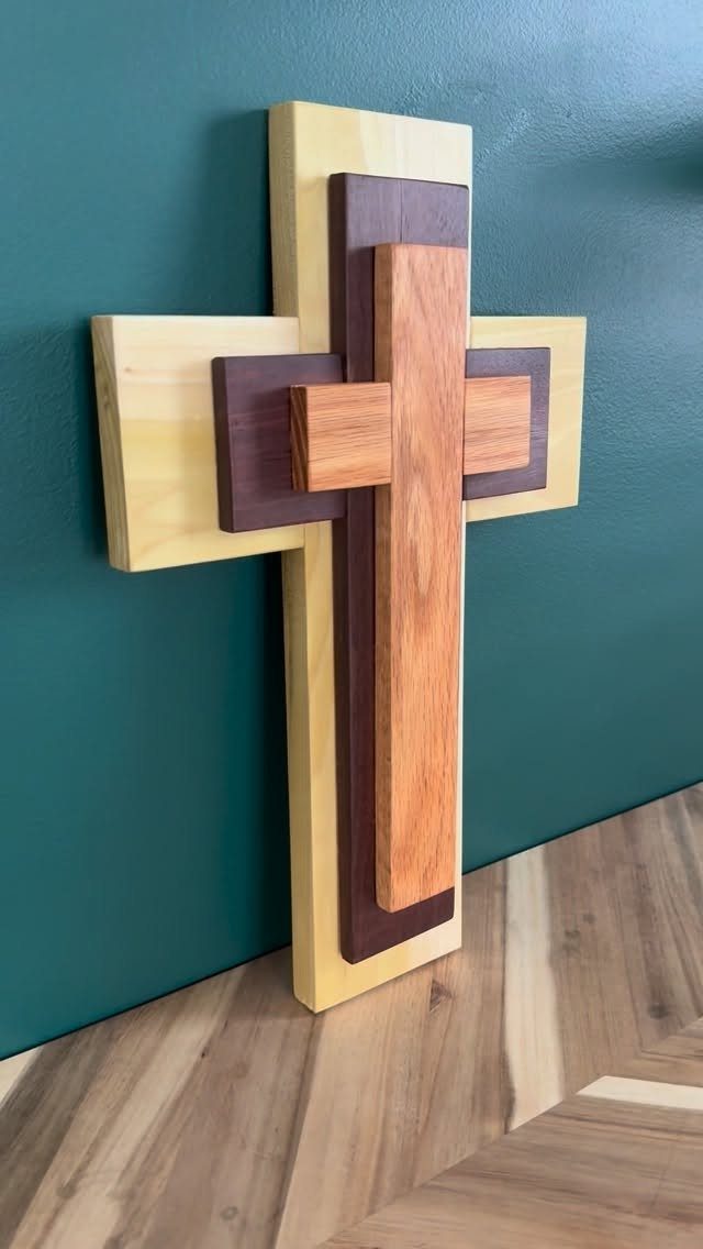 DIY Wooden Crosses: 5 Ideas, from Woven to Carved 2 Layered wooden cross in three different wood tones mounted on a teal wall