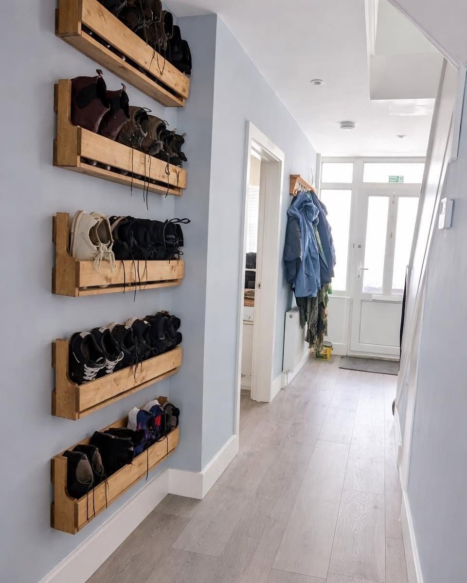 Wooden wall mounted shoe racks holding various footwear in a bright home hallway.