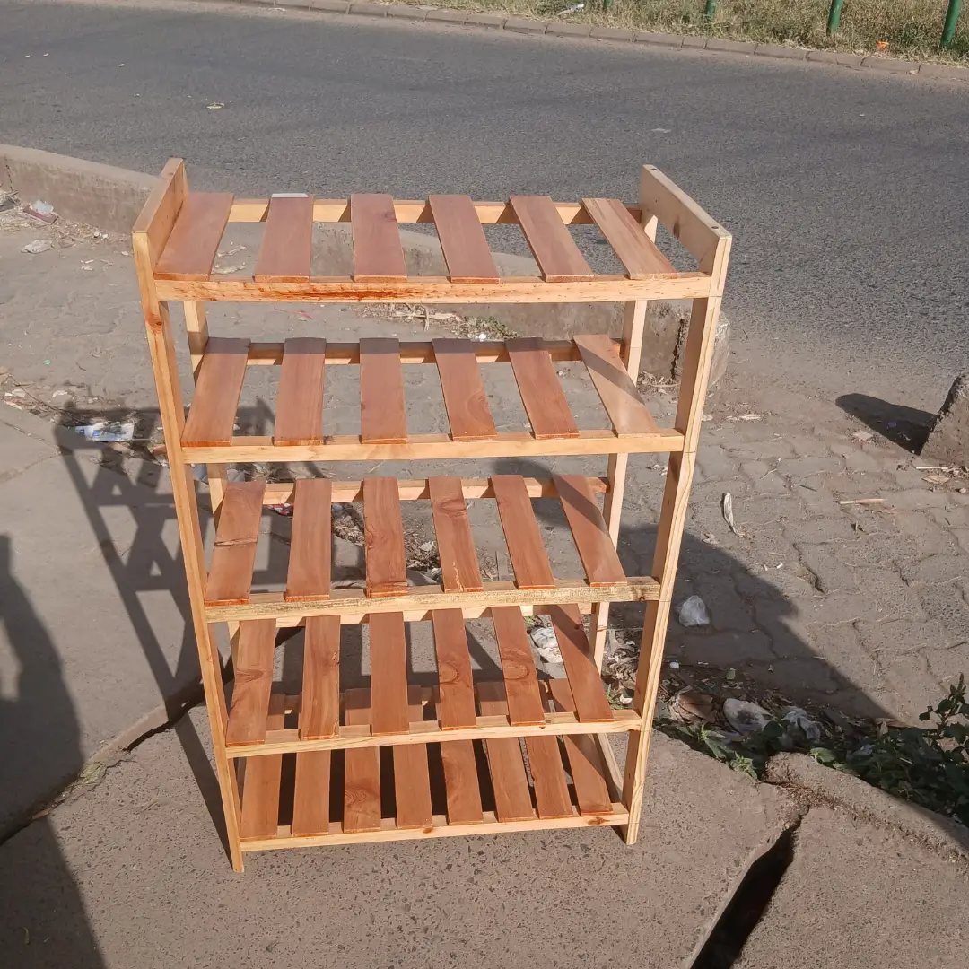 Five-tier light brown wooden shoe rack standing on a concrete sidewalk.