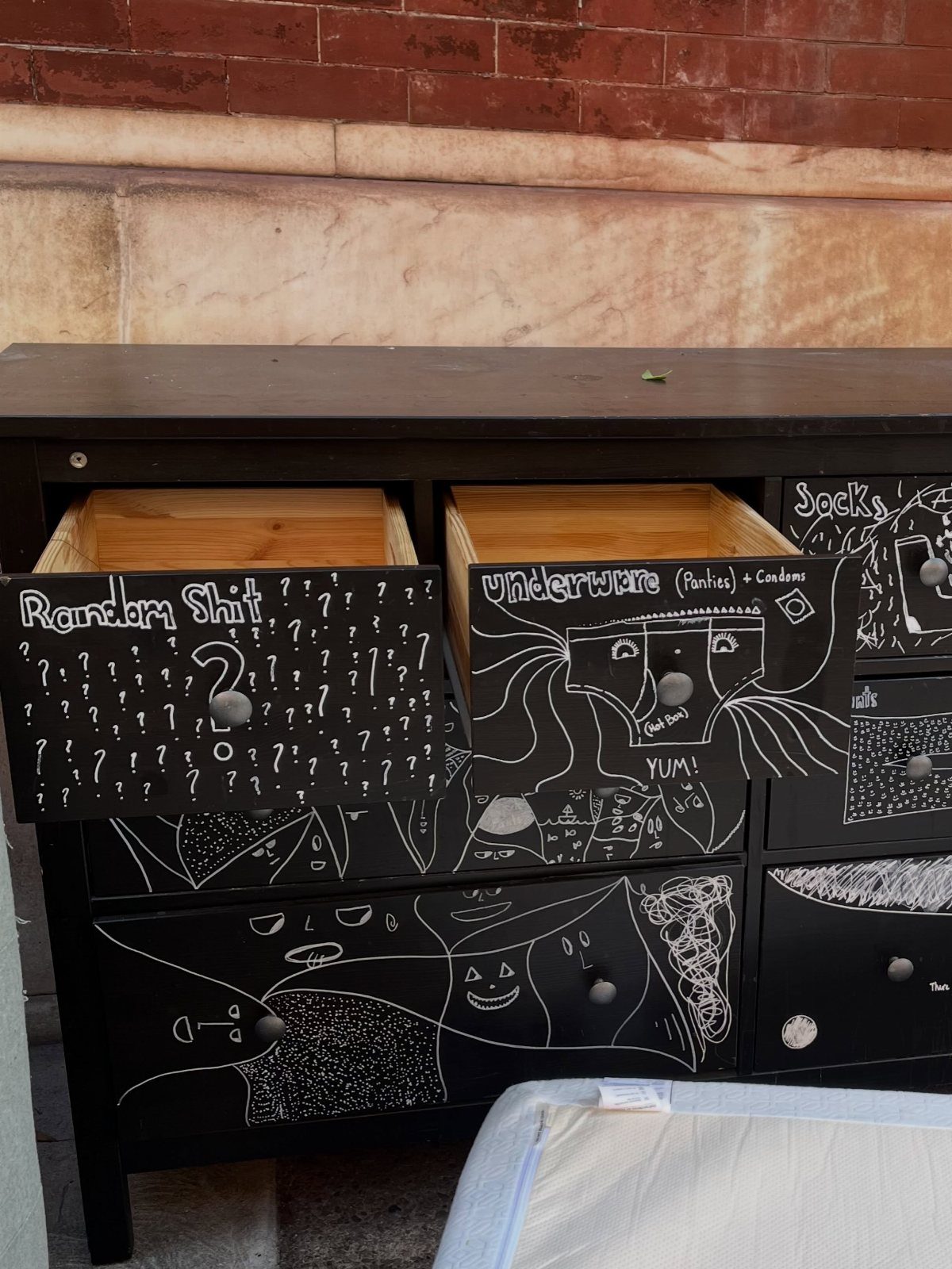 Black dresser with chalkboard paint and white chalk drawings on the drawers.