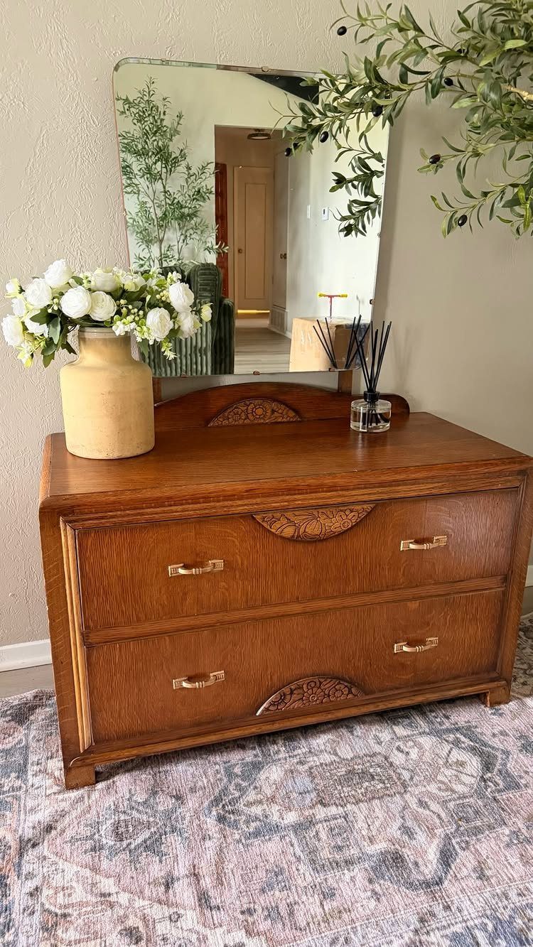 Wooden dresser with carved decorative wood appliqués on the drawers and top edge.