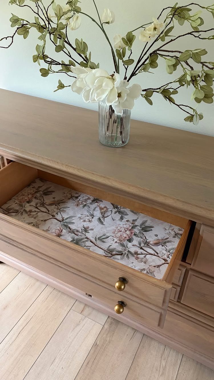 Light wood dresser with an open drawer featuring a floral patterned liner.