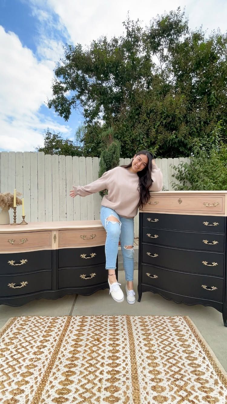 Two black and beige painted dressers with gold handles standing on a patterned rug.