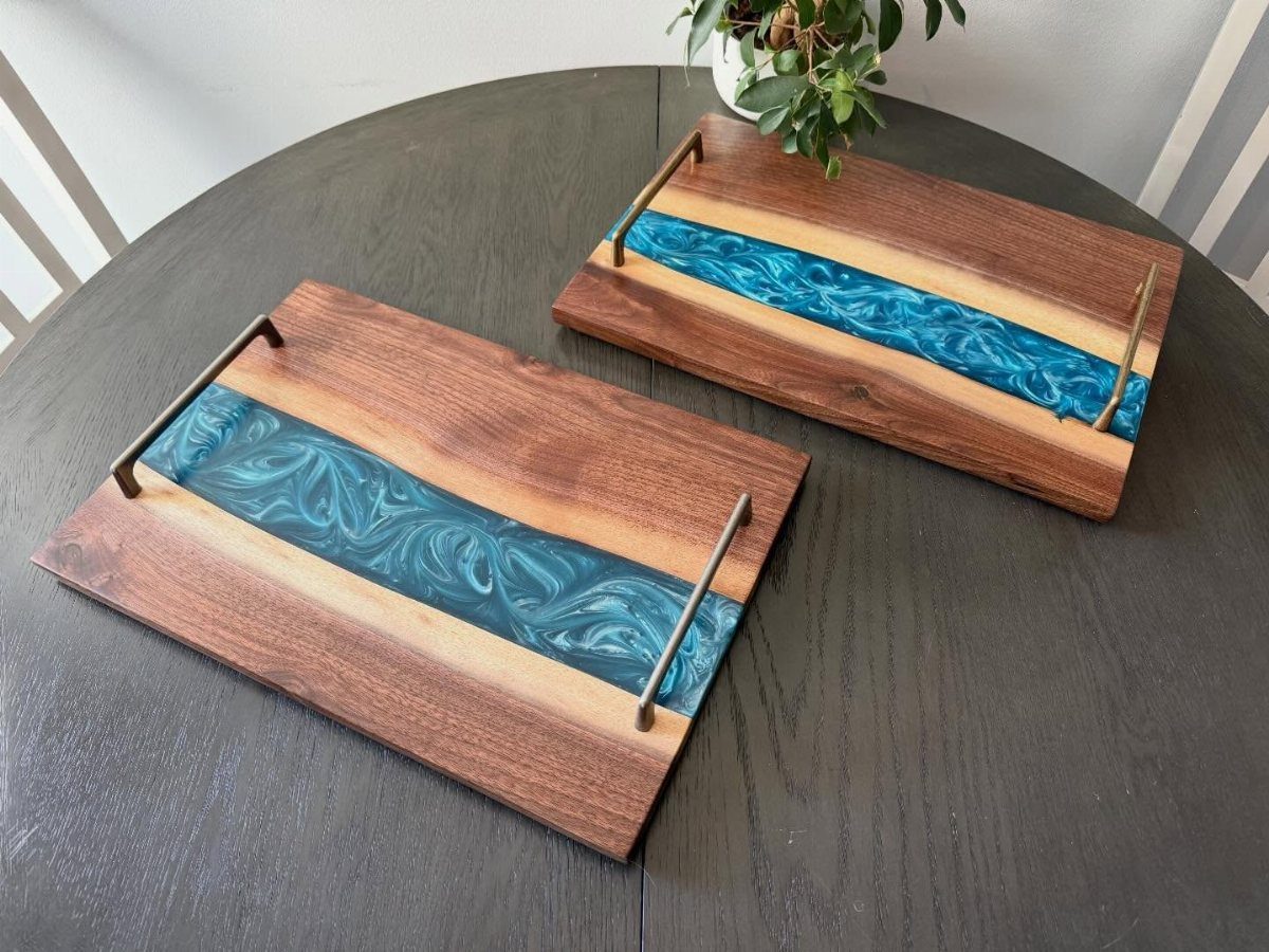 9 Epoxy Resin Wood Projects: Tables, Trays, Clocks and Coasters 4 Two wooden serving trays with blue epoxy resin river centers and gold handles.