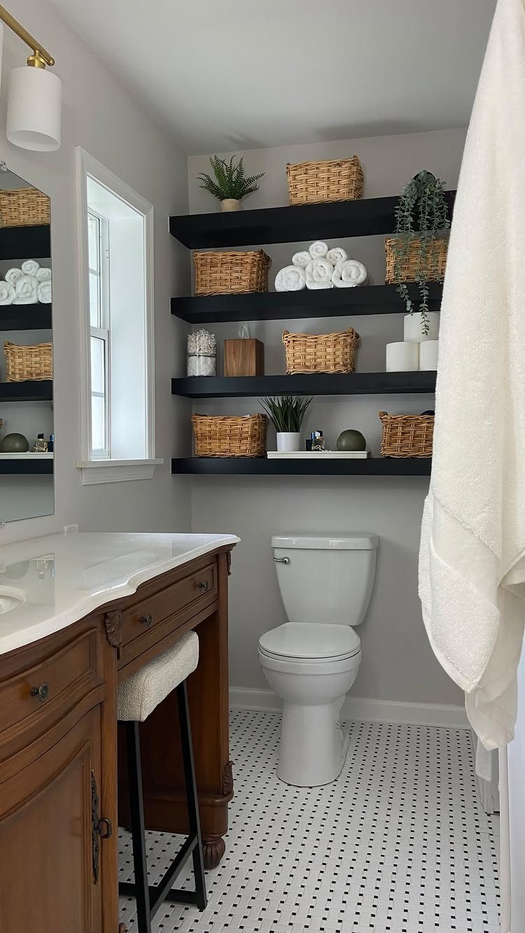 Black floating wooden shelves with baskets and towels in a modern grey bathroom