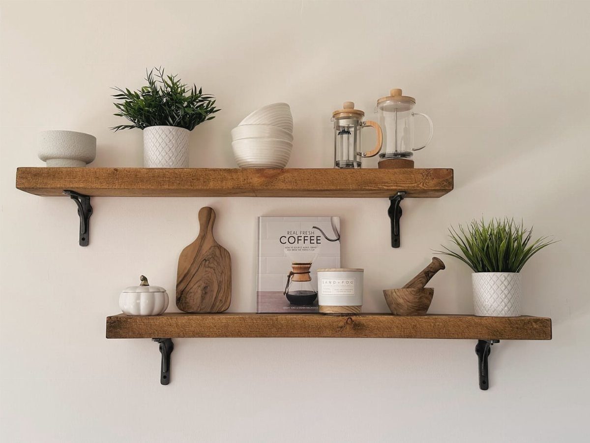 Rustic wooden shelves with black metal L brackets holding kitchen decor on white wall