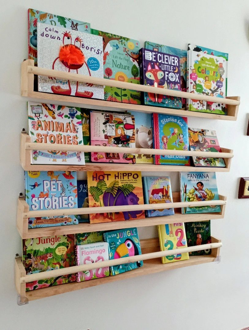 Wooden floating bookshelves on a white wall filled with colorful children's books