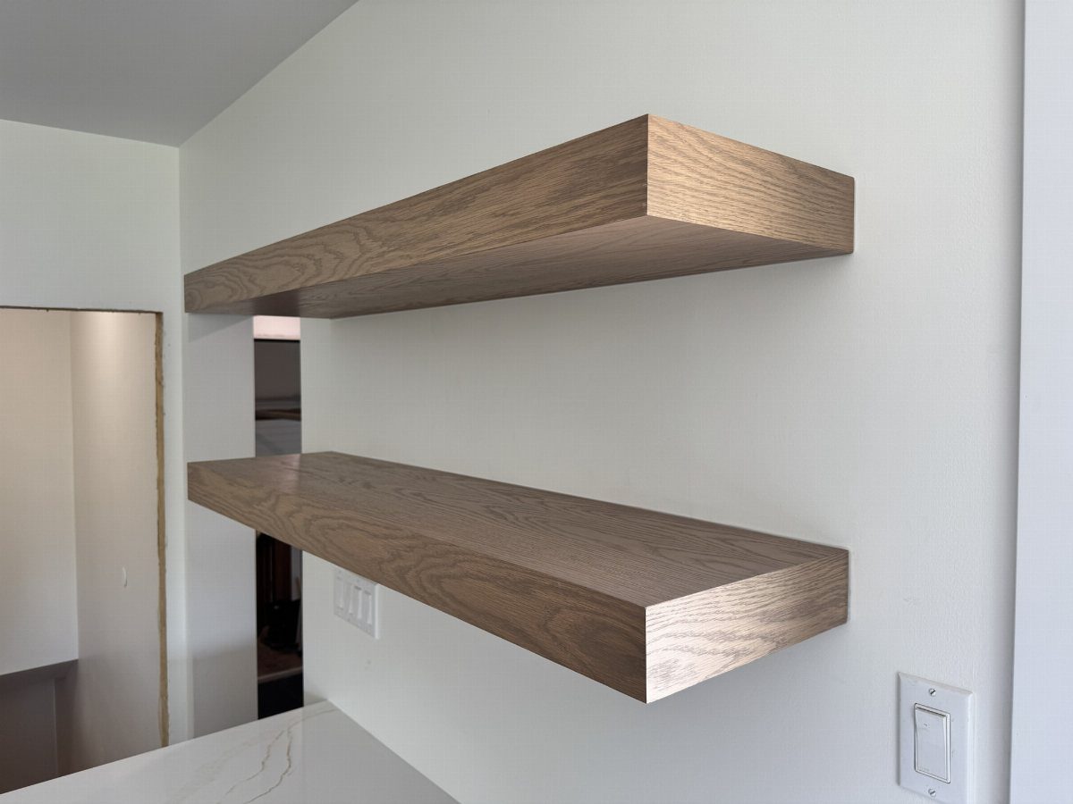 Two thick light-brown wooden floating shelves mounted on a clean white wall.