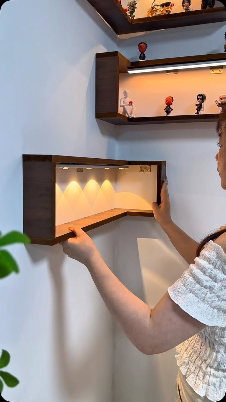 Dark wood floating corner shelf with integrated LED lighting mounted on a blue wall.