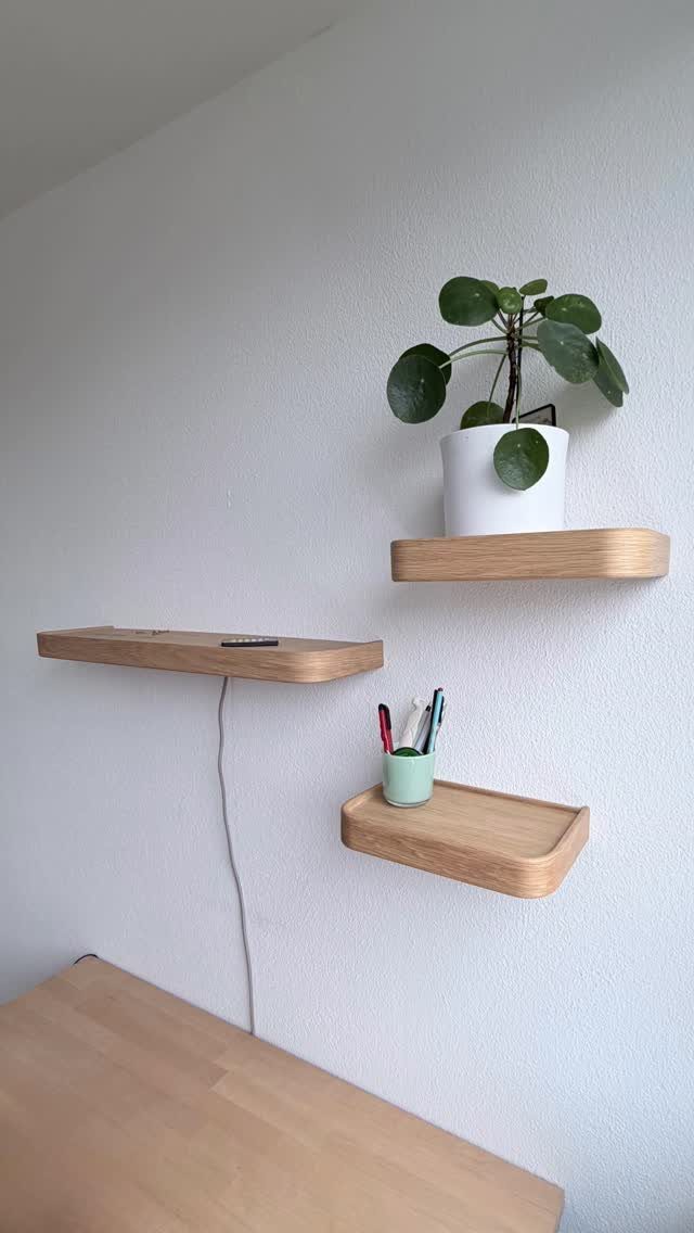 Light wood floating shelves on a white wall with a potted plant.