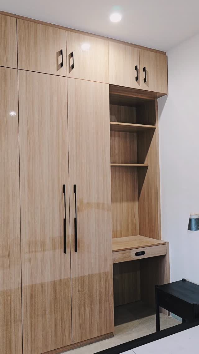Light wooden built-in wardrobe with integrated desk and open shelving against white wall