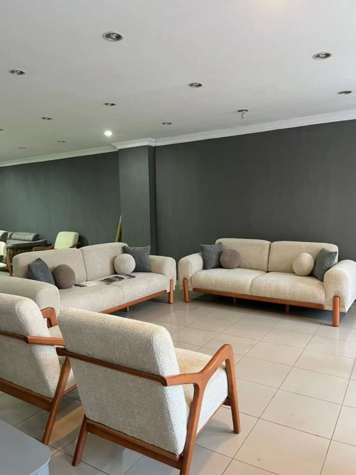 Cream fabric sofas and armchairs with light brown wooden frames in a modern room.