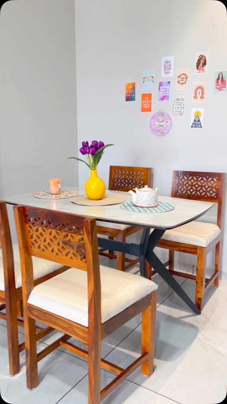 Wooden dining set with a light tabletop, black legs, and four carved chairs.