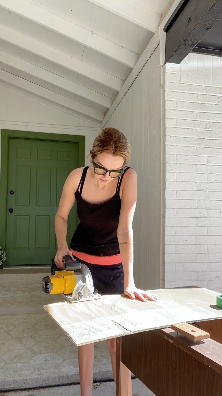Furniture Making Tools: 11 Hand and Power Tools to Own 9 Woman using a yellow circular saw to cut plywood on a wooden workbench.