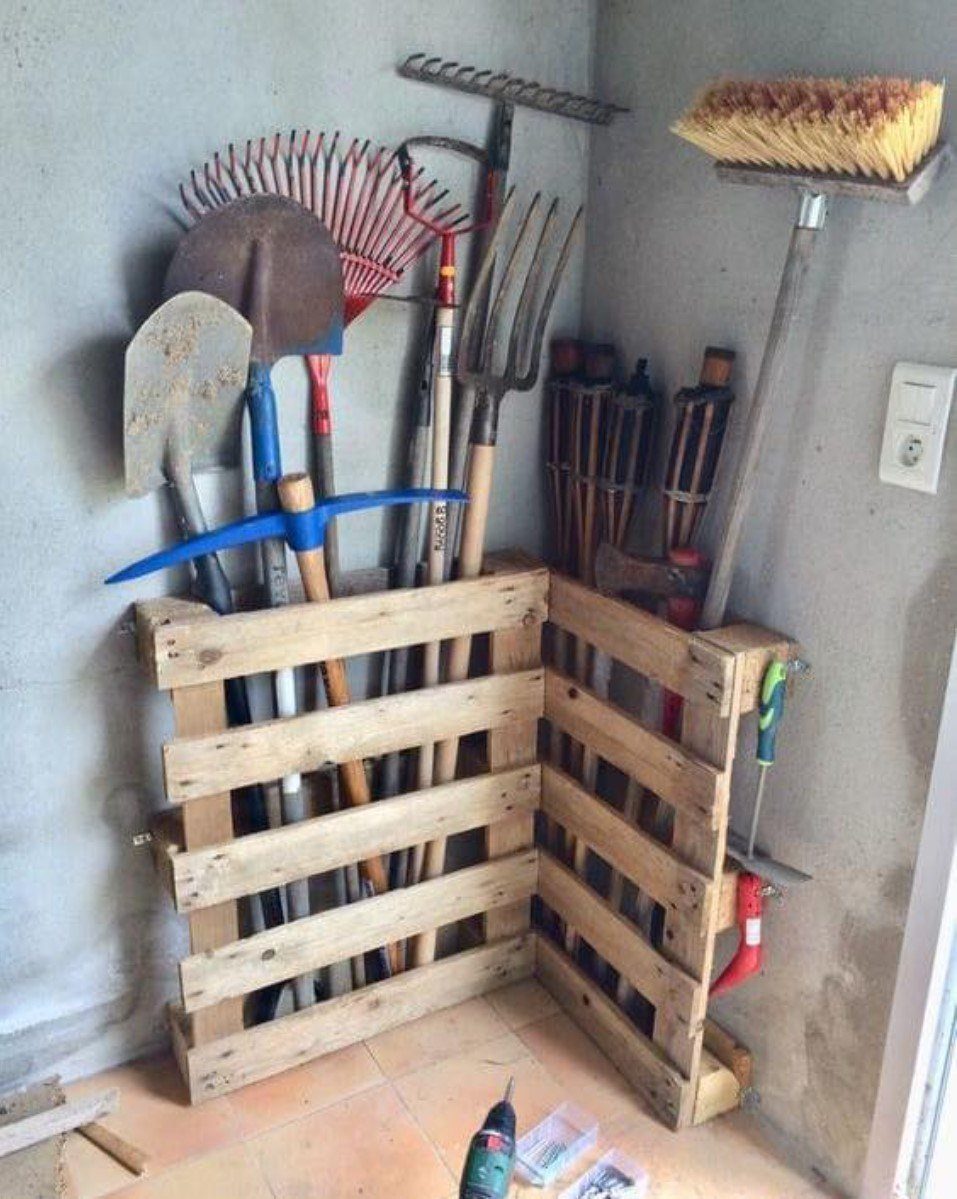 10 Garden Tool Storage Ideas for Any Yard or Garage 3 Wooden pallet storage rack holding various garden tools in a room corner.