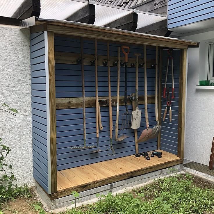 10 Garden Tool Storage Ideas for Any Yard or Garage 2 Blue wooden garden shed with various tools hanging on a wall rack.